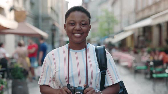 Black Woman Standing on Street with Retro Camera on Neck