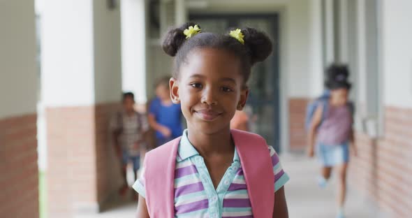 Video of happy african american girl standing at school corridor alt