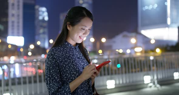 Woman look at mobile phone in city at night