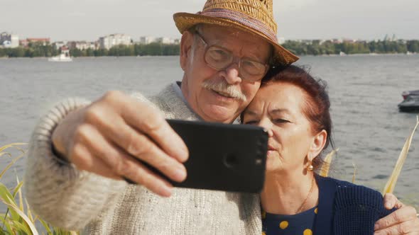 Front view close up of Caucasian smiling senior couple taking selfies at promenade