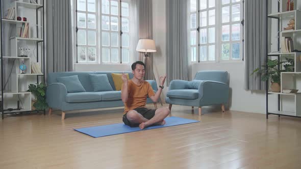 Asian Man Doing Yoga In Easy Pose On Mat At Home