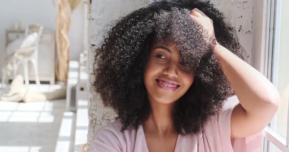 Relaxing Smiling Young Black Woman is Sitting Woman Sitting Near Window