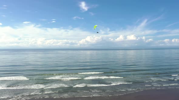 A paraglider flying over the Pacific Ocean on a beach in Costa Rica