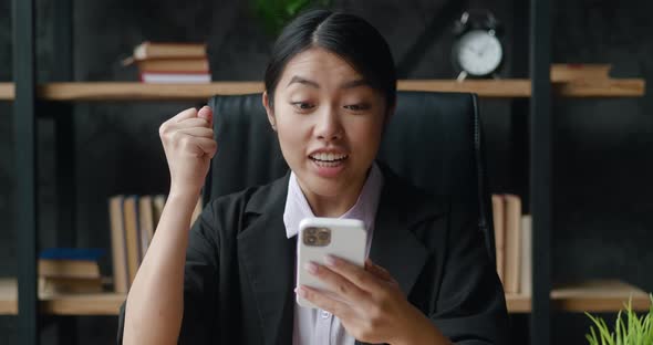 Portrait of Happy Business Woman Enjoy Success on Smartphone Sitting at Modern Office