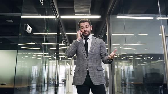 Businessman which Walking Through the Modern Company Hall and Talking on Smartphone