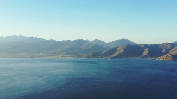 Misty morning over peaceful tropical landscape with clear sky, panoramic mountains and blue azure se