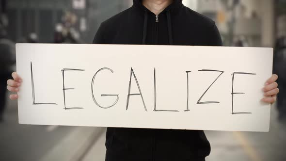 Activist Wearing Black Holds a Placard with LEGALIZE Text