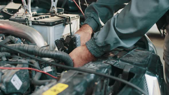 Cropped Image of Auto Mechanic in Uniform Repairing Car in Auto Service