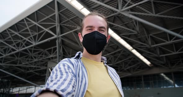 Young man with face mask taking selfie at the airport.