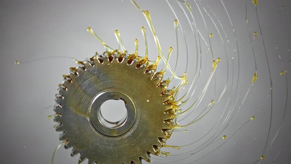 Super Slow Motion Shot of Rotating and Splashing Metal Cogwheel on Grey Background at 1000 Fps