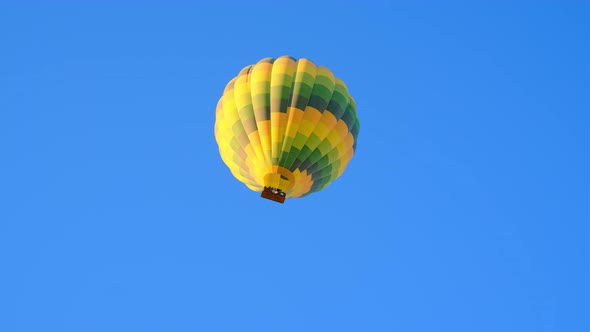 Beautiful Bright Yellow Green Hot Air Balloon Flies in Bright Blue Cloudless Sky