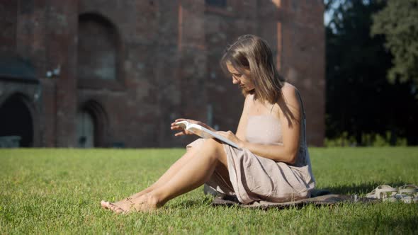 Woman reading a book near the old building