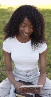 Outdoor Portrait of a Smiling Black Girl Using a Tactile Tablet