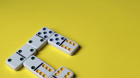 Hands of a young caucasian woman playing stacking dominoes on yellow.
