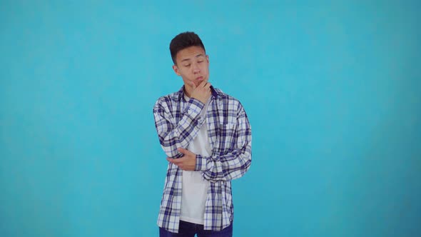 Thoughtful Young Asian Man Find Solutions on Blue Background