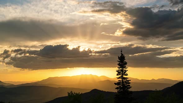 Beautiful sunset time-lapse as sun lights up the clouds with single tree