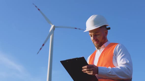 A Male Engineer in a White Helmet a Classic Shirt and an Orange Work Vest Inspects the Power Plant's