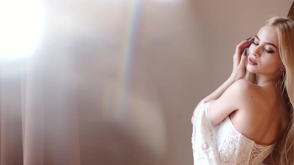 Young Blonde Woman in Elegant White Dress Posein Studio