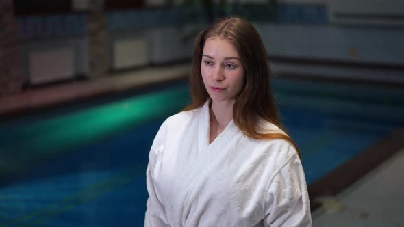 Live Camera Zoom in to Happy Confident Young Woman Standing at Pool Indoors Looking Away and Posing