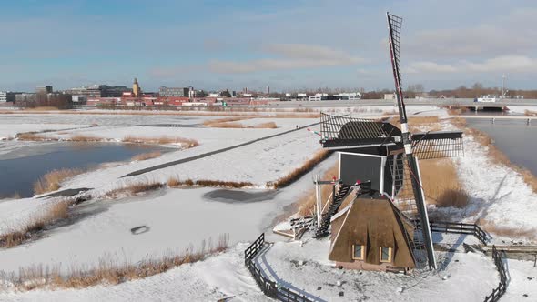 Iconic Dutch windmills covered in winter snow and ice, cold winter aerial view