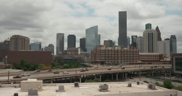 Establishing shot of downtown Houston on a cloudy day as cars pass by on freeway