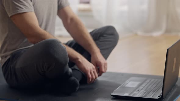 Unrecognizable Man Turning on Online Lesson on Laptop and Sitting in Lotus Pose