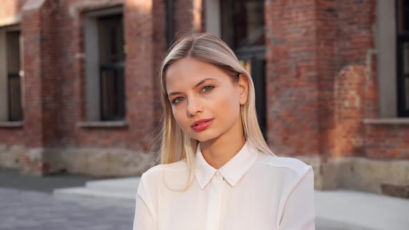 Portrait of Smiling Beautiful Young Blond Woman Standing in Urban Street