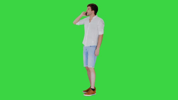 Happy Young Man Talking on Mobile Phone and Smiling on a Green Screen, Chroma Key