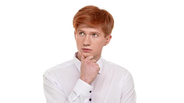 Thoughtfull Caucasian Young Boy with Ginger Hair Standing on White Background and Holding His Chin