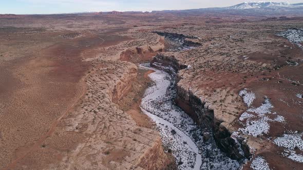 Aerial view flying down into canyon from above the desert in Utah
