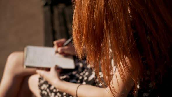 Redhead Young Girl Gently Writing Notes While Wind Slightly Blowing Her Hairin Slowmotion