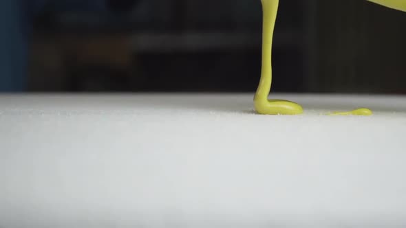 Beautiful slider shot of epoxy resin for surfboard glassing process. Smoothly pouring yellow paint o