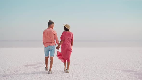 Stylish Elegant Couple Walking on White Salty Coast Looks Like Desert Honeymoon Vacation