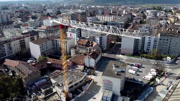 Drone Shot of a Crane in a Construction Site with a Cityscape behind