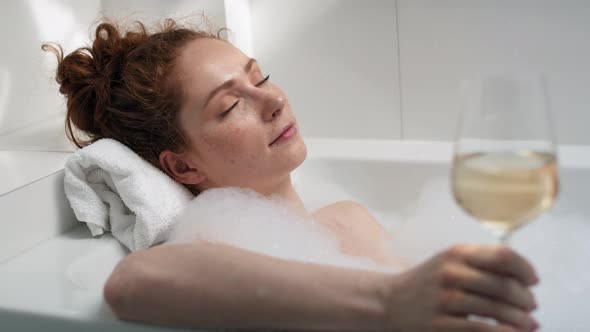 Caucasian redhead woman taking a bath and drinking wine. Shot with RED helium camera in 4K.