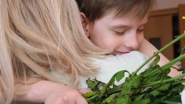 caucasian boy 7 years old hugging his blonde mom and giving a bouquet of fresh flowers.slow motion.m