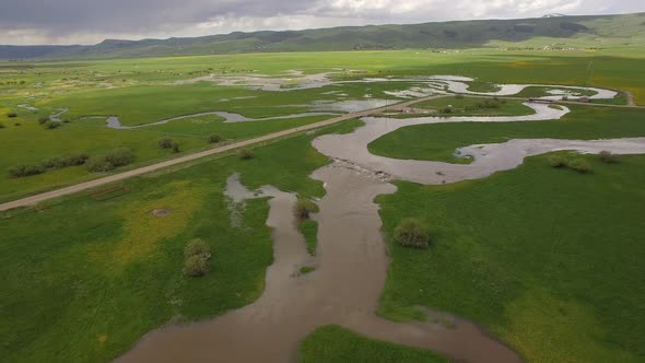 Aerial view flying down towards river winding through pasture