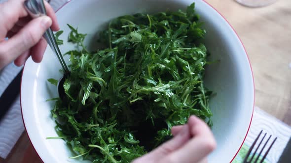 A man mixing the rocket salad.