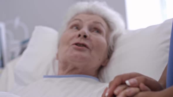 Nurse Supporting Old Lady in Hospital Ward