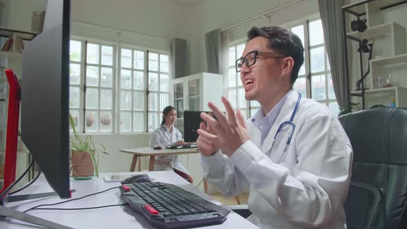 Asian Male Doctor Communicates With Patient By Video Link, Doctor Consults Patient