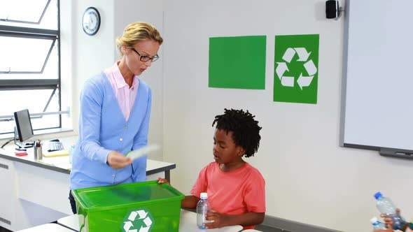 School kids looking recycle logo box in classroom