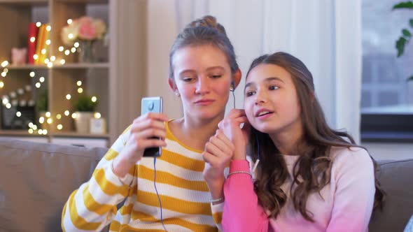 Happy Girls with Smartphone and Earphones at Home