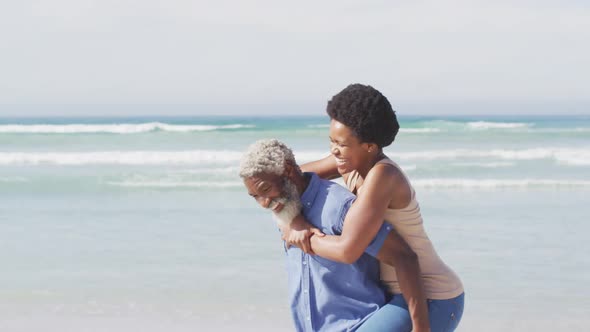 Happy african american couple walking and embracing on sunny beach