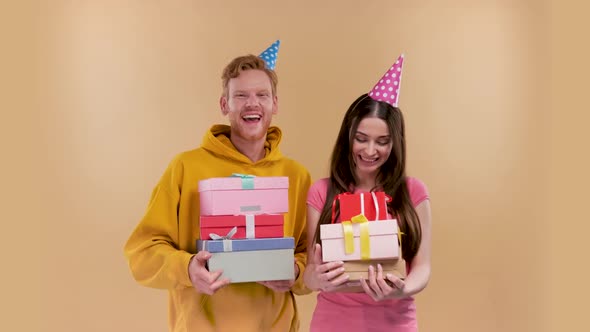a Man and a Woman are Holding a Lot of Gift Boxes Isolated Over Beige Background