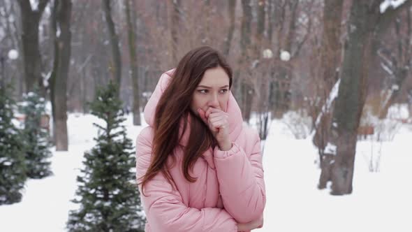 A Beautiful Woman Tries To Warm Her Frozen Hands with Her Breath on a Winter Outdoors