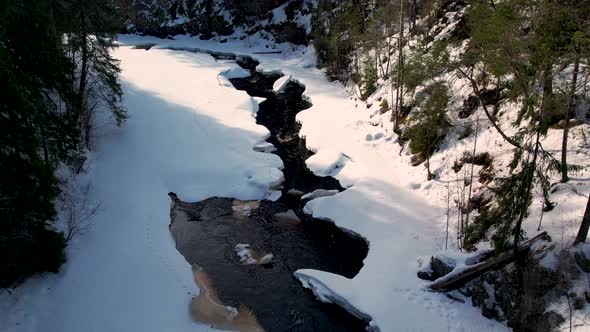 Aerial view of a snow-covered river in Swedish forest during Winter