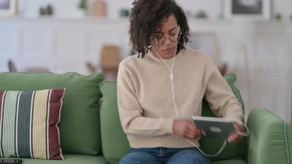 Young African Woman Meditating on Tablet on Sofa