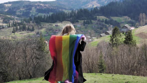 Person Holding LGBT Flag on Mountains Background