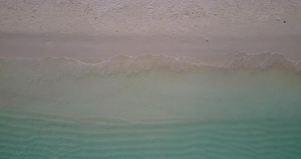 Wide overhead clean view of a sandy white paradise beach and blue ocean background in high resolutio