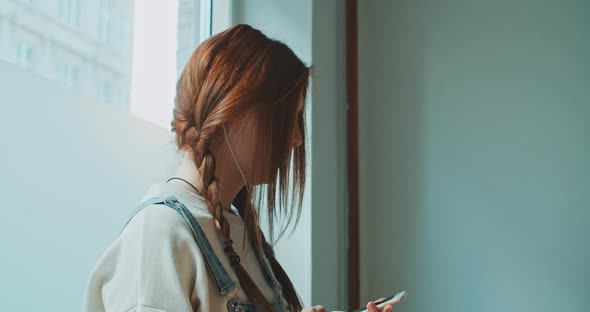 Attractive young woman with red hair using a smartphone